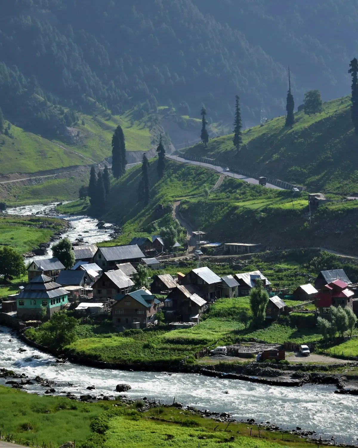 A green river valley with a village beneath high mountains in Ghizer